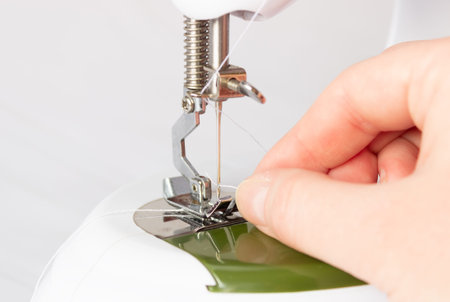 The process of threading the thread into the needle eye of a sewing machine.