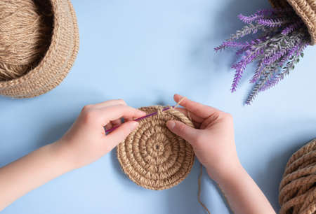 Hands crochet a round napkin made of jute. Hobbies, needlework.の写真素材