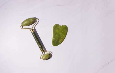 A gua sha roller and a jade stone scraper on a white background. Chinese massage techniqueの写真素材