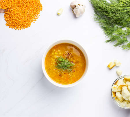 Red lentil soup with ingredients on a light background. Traditional Turkish or Arabic spicy lentil and vegetable soup, healthy vegan food. Top view.の写真素材
