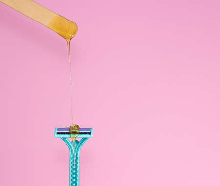 Sugar paste for hair removal against a razor. Sugaring paste drips on a razor on a pink background, copyspace. The concept of epilation, spa, body care.の写真素材