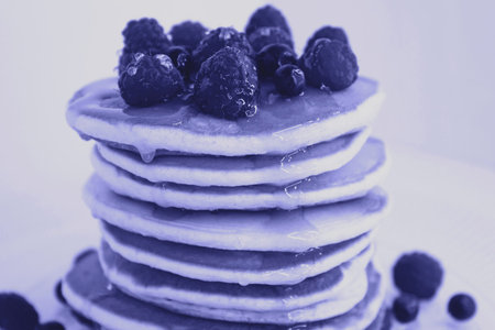 American pancakes with fresh berries and honey. Healthy morning breakfast toned in the color of 2022...