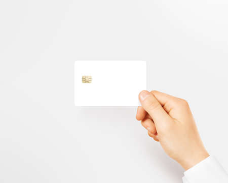 Hand holding blank white credit card mockup isolated. Empty plastic card mock up hold in arm. Clear surface bank card with electronic chip. Debit card concept design presentation template.の写真素材