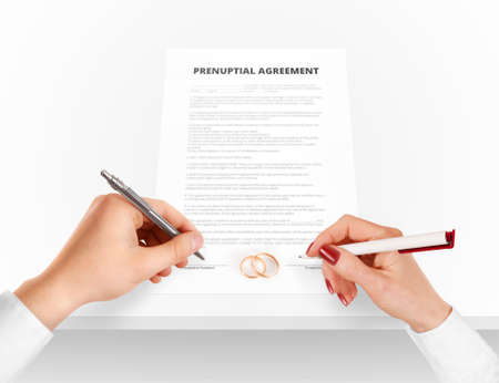 Man and woman sign prenuptial agreement near gold rings.の写真素材