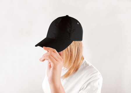 Blank black baseball cap mockup template, wear on women head, isolated, side view. Woman in clear grey hat and t shirt uniform mock up holding visor of caps. Cotton basebal cap design on delivery guy.の写真素材