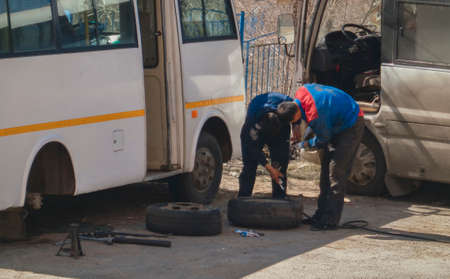 Kazakhstan, Ust-Kamenogorsk, april 11, 2019: Men fix the bus. Wheel upのeditorial素材