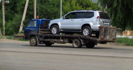 Kazakhstan, Ust-Kamenogorsk, july 7, 2019: Gray broken SUV on a blue towing truck. Vehicle mechanical problem on the road. Old tow truckのeditorial素材