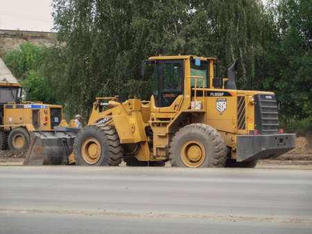 Kazakhstan, Ust-Kamenogorsk, August 21, 2019: Wheel loader Lovol FL956F. Road construction. Chinese construction engineering. Grunge urban landscapeのeditorial素材