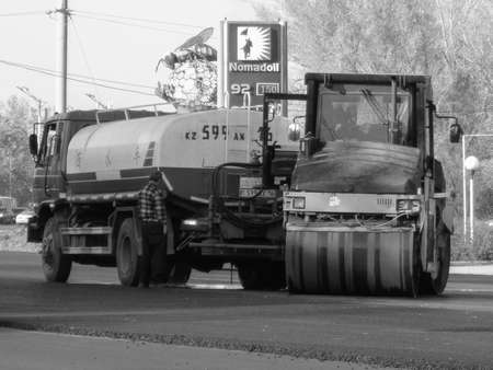 Kazakhstan, Ust-Kamenogorsk, September 10, 2019: Steamroller and tank truck. Worker. Black and whiteのeditorial素材