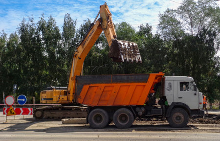 Kazakhstan, Ust-Kamenogorsk, august 13, 2017: Truck Kamaz 5511 and excavator Hyundai at work....