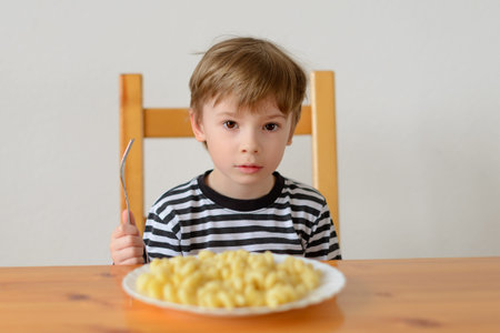 A boy sits at a table with a pasta dishの写真素材