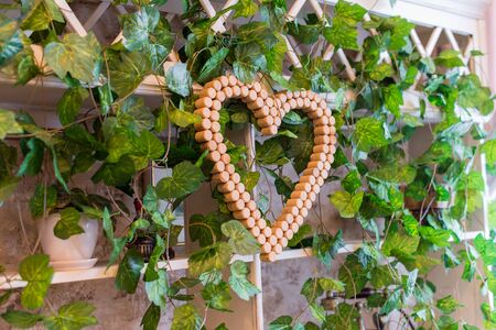 wedding festive wall decor of wine corks in the shape of a heart among the decorative leaves of the vineの写真素材