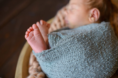protruding pink heels of a sleeping newborn baby wrapped in gray-blue knitted fabricの写真素材