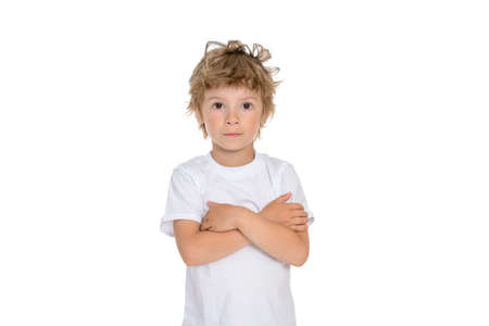 Photo of a boy on a white background with folded hands on his chest in a white T-shirt and a straight look at the camera, the boy has brown eyesの写真素材