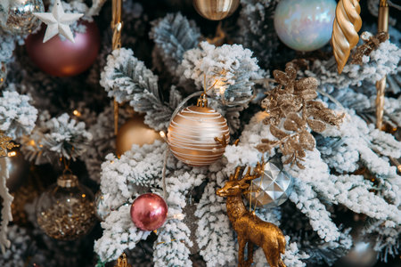 Close-up of decorated christmas tree branches decorated with orange, red and blue balls, toy deer