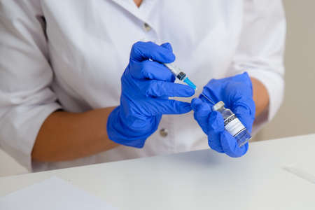 Doctor filling a syringe with medicine, close-up. Vaccination and immunization against covid-19の写真素材