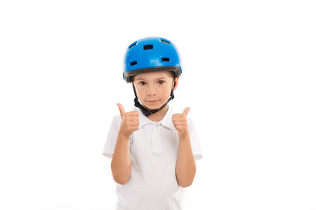 A boy in a blue helmet shows a gesture of big hands up, he does not smile, a calm expression on his face. Stands on white isolated backgroundの写真素材