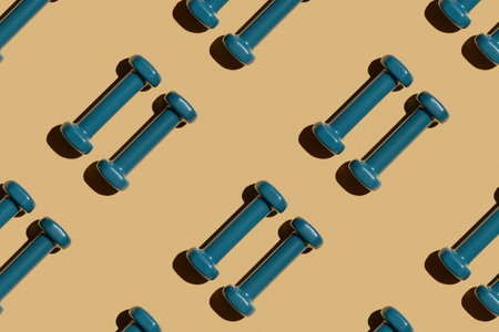 Two blue fitness dumbbells on a beige background lie parallel, pattern, top view, close-upの写真素材