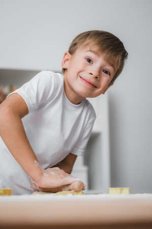 Little boy rolls out raw dough with a wooden rolling pinの写真素材