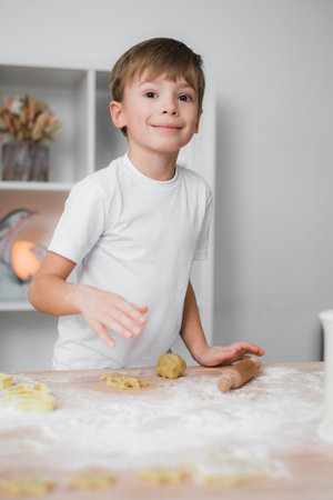 Home cooking. A child boy is engaged in cooking cookies, looks at the camera and smiles, he is happyの写真素材