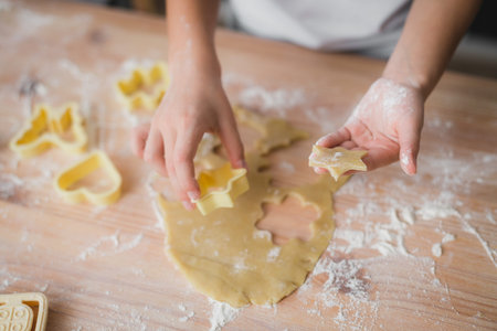 Cooking and home concept - close up of kid hands making fresh dough cookies at home