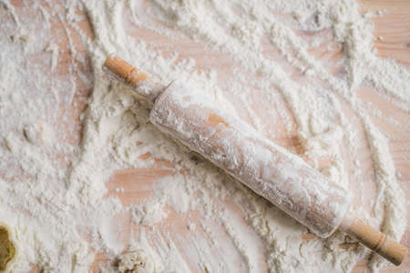 Close-up wooden rolling pin lying on the kitchen table with flourの写真素材