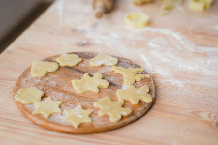 Close-up shot of cutting board with raw dough cookie cuttingsの写真素材