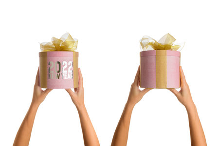 Female hands with round pink gift box tied with yellow bow and text new year 2022 on white isolated...