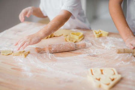 Close-up of a child's hand laying out blanks of raw dough biscuits on the kitchen tableの写真素材