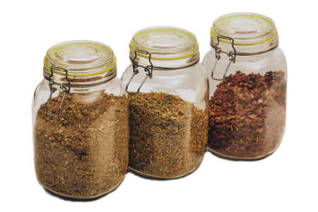 three glass jars with tight lids, herbal teas of different varieties inside, isolated on a white backgroundの写真素材