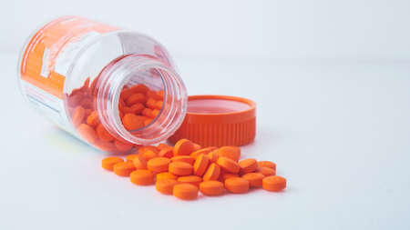 orange pills spilled out of a can on a white table, background image, macroの写真素材