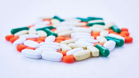 white, green, orange, yellow pills are scattered on the table, soft focus, macro, white backgroundの写真素材