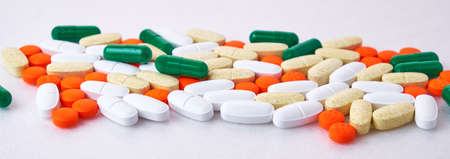white, green, orange, yellow pills are scattered on the table, soft focus, macro, white backgroundの写真素材