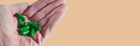 green capsules with drug lie on a man's wrinkled palm, isolated image on background, banner conceptの写真素材