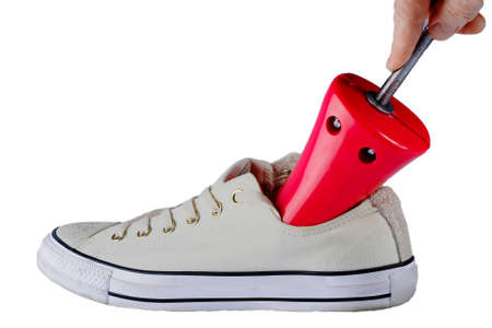device of red color for stretching shoes man's hand inserts into a white sneaker, white backgroundの写真素材