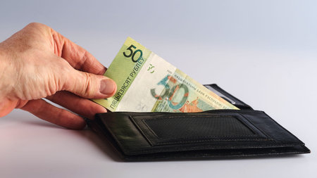 a man's hand takes out a green bill from a black partmoneの写真素材