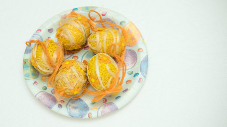 Handmade colored Easter eggs on a plate decorated with thread