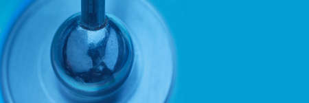 abstraction, dark rough metal ball with mount presses the center of a blue CD, banner concept, space for textの写真素材