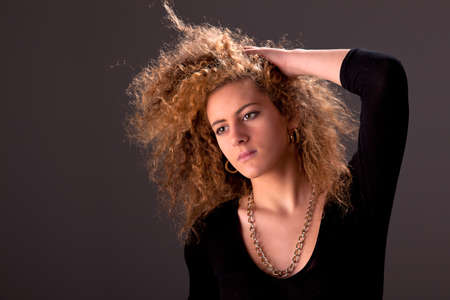 Beautiful woman  with hands holding the hair, looking to camera, studio shotの写真素材