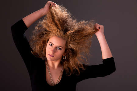 Beautiful woman  with hands holding the hair, looking to camera, studio shotの写真素材