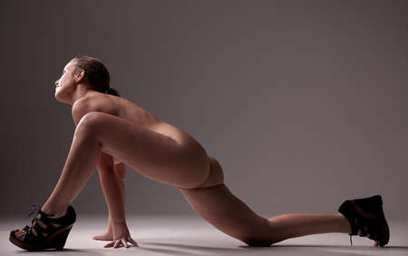 picture of healthy naked woman, kneeling looking to light, studio shootの写真素材