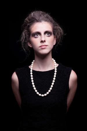beautiful young woman with elegant black dress, on black background, studio shotの写真素材