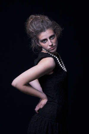 beautiful young woman with elegant black dress, on black background, studio shotの写真素材