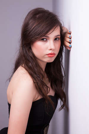 beautiful young woman, looking to camera, against the wall, studio shotの写真素材