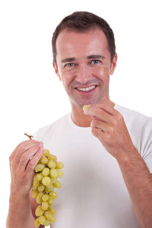 handsome man eating a green grapes, isolated on white background. Studio shot.の写真素材