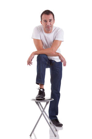 Portrait of a handsome middle-age man with his foot on a bench, on white background. Studio shotの写真素材