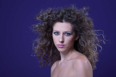 beautiful woman with curly hair on wind, on purple, studio shotの写真素材