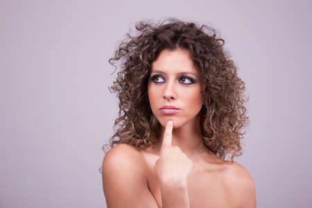 thoughtful and beautiful woman with curly hair, remember something, studio shotの写真素材