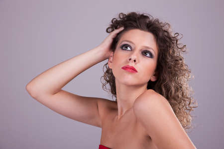 beautiful woman with curly hair, holding the hair, studio shotの写真素材
