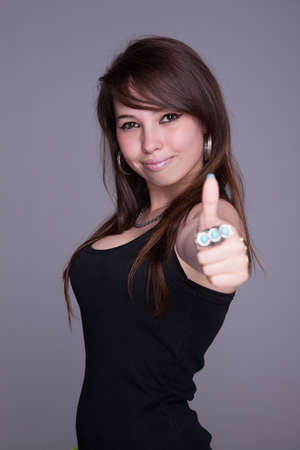 beautiful and happy young woman, with tumb up, studio shotの写真素材